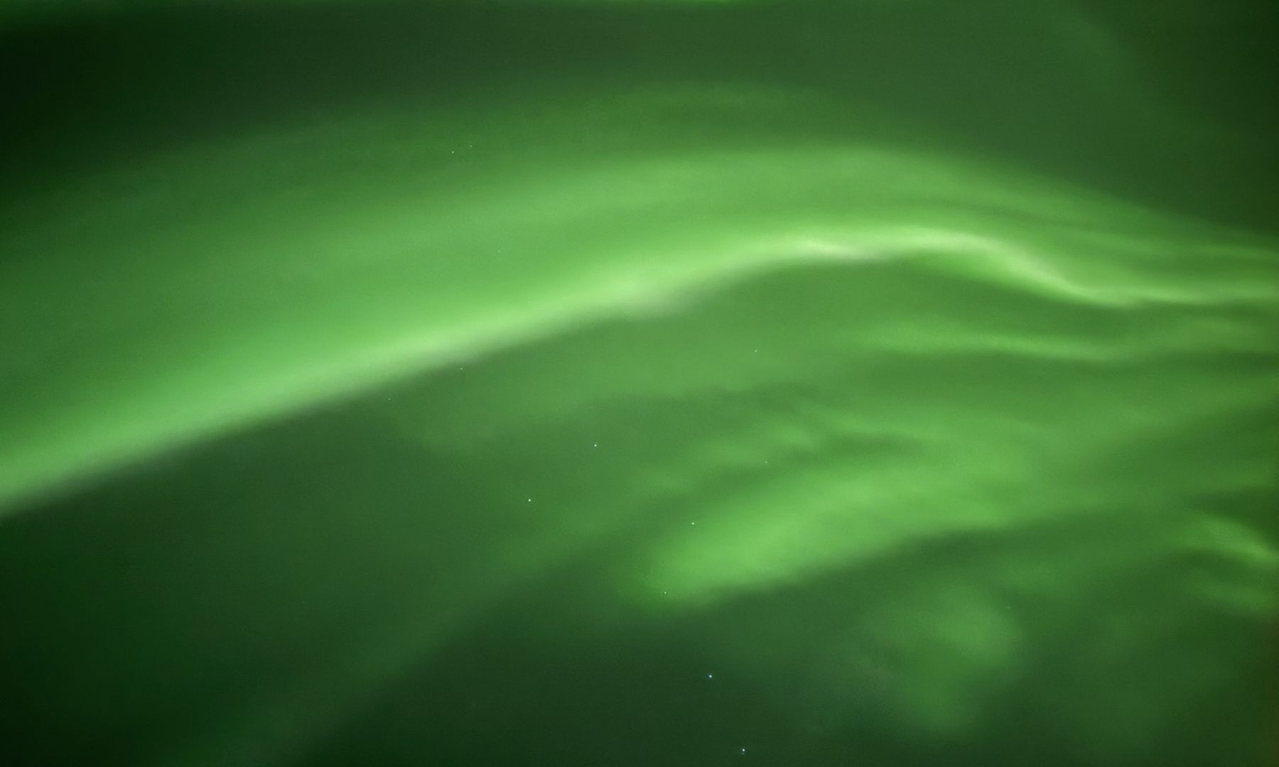 Arco de aurora boreal verde cruzando el cielo nocturno