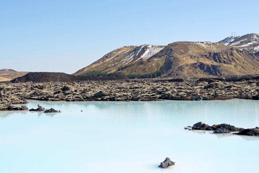 Agua azul lechosa de la Blue Lagoon entre campos de lava con el monte Þorbjörn al fondo
