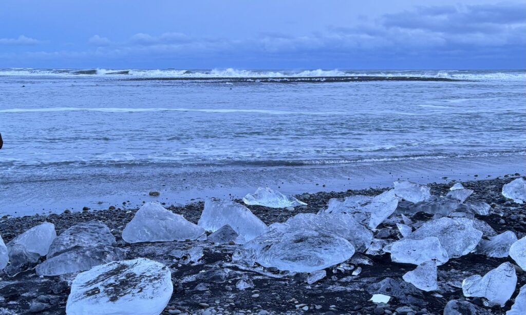 Bloques de hielo sobre la arena negra de Diamond Beach con el mar al fondo