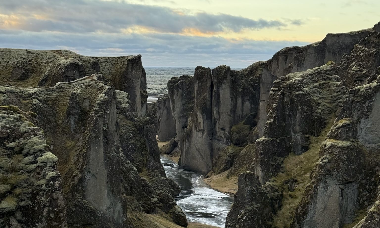 Paredes de roca verdes y grises del cañón de Fjaðrárgljúfur con el río abajo