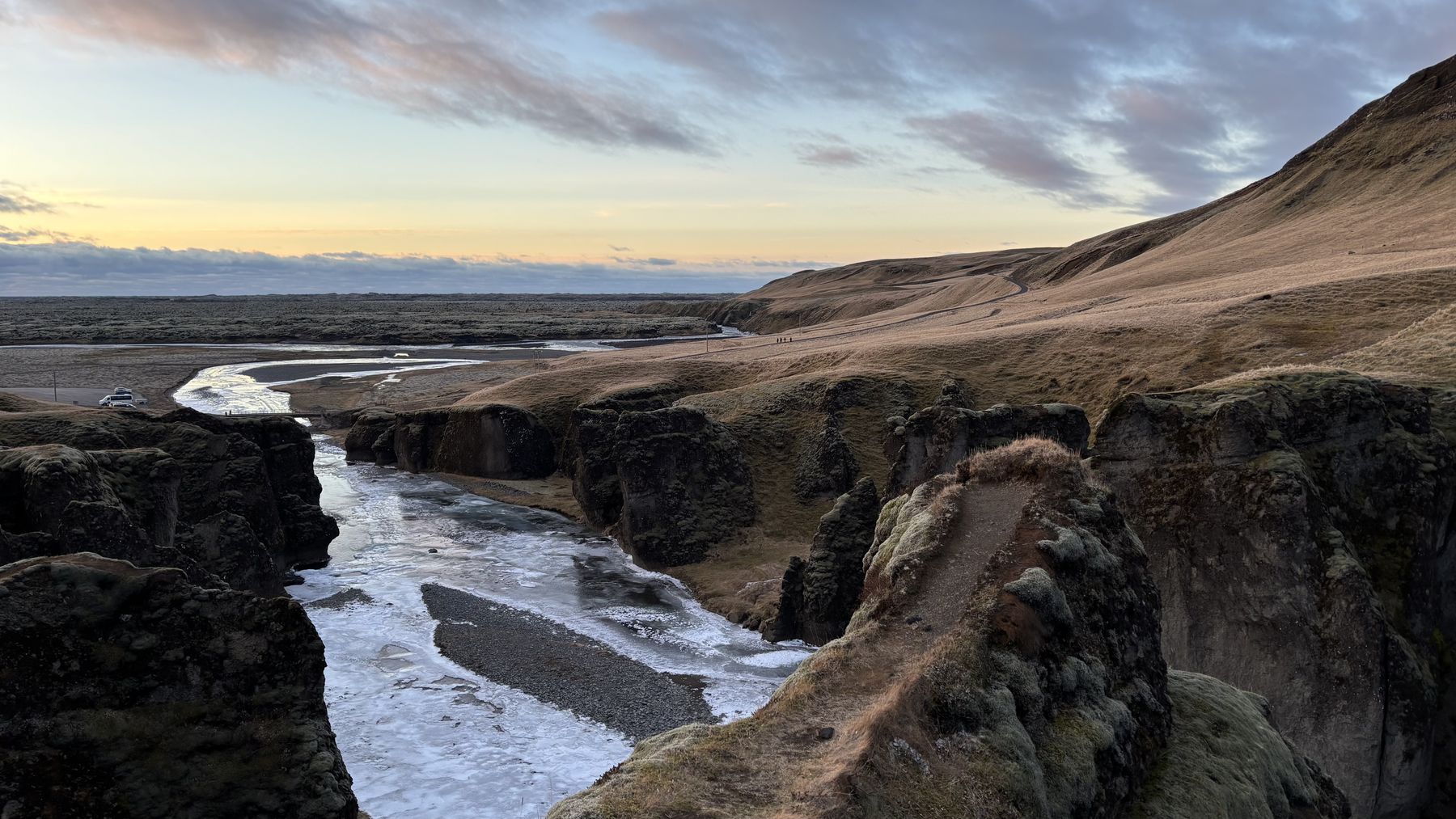 El cañón de Fjaðrárgljúfur serpenteando con el río helado al fondo al atardecer