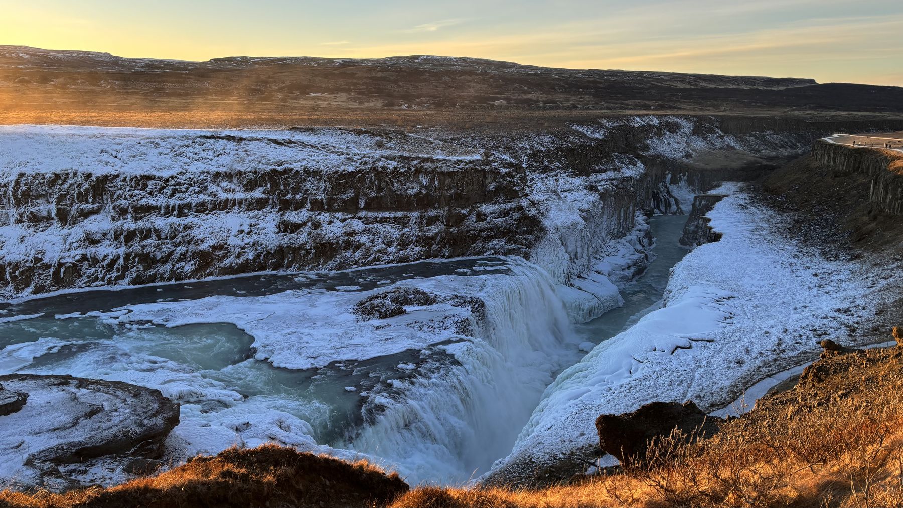 La cascada de Gullfoss medio congelada cayendo en un cañón nevado al amanecer