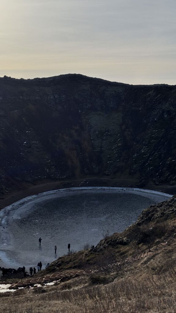 Lago helado en el fondo del cráter de Kerið con gente caminando a lo lejos