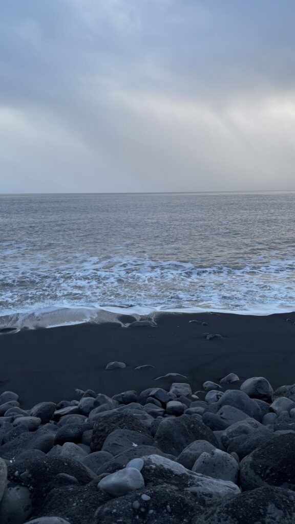 Cantos rodados negros en la orilla de Reynisfjara con el mar gris