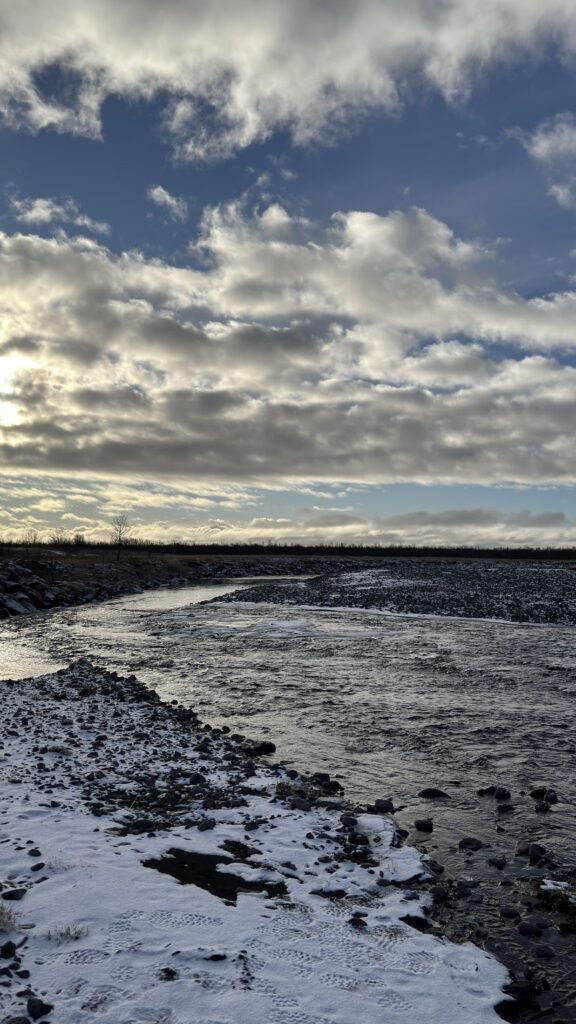 Río entre orillas nevadas y cielo con nubes